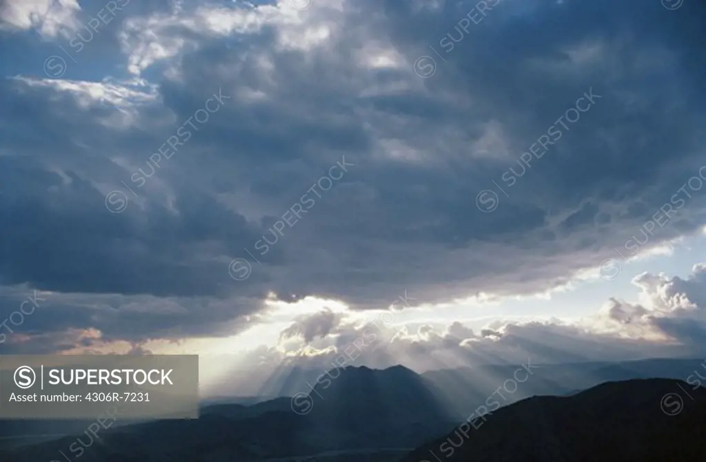 Sunlight seeping through clouds over mountains