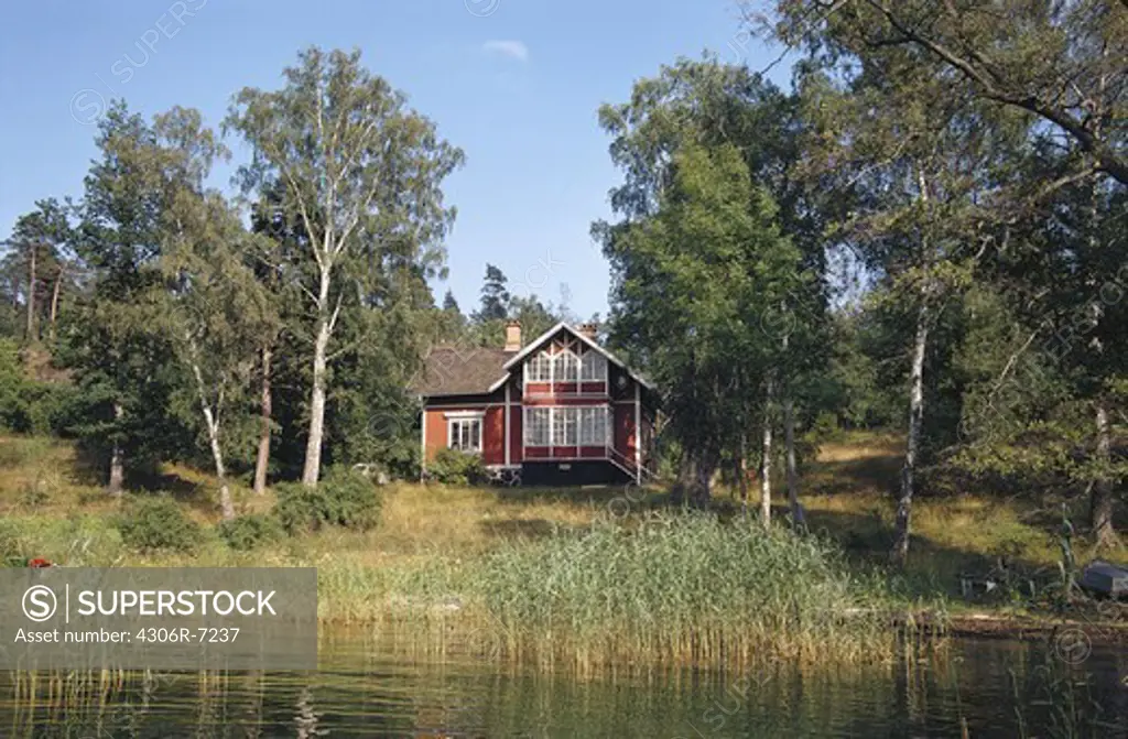 Exterior of house surrounded by trees on bank of lake