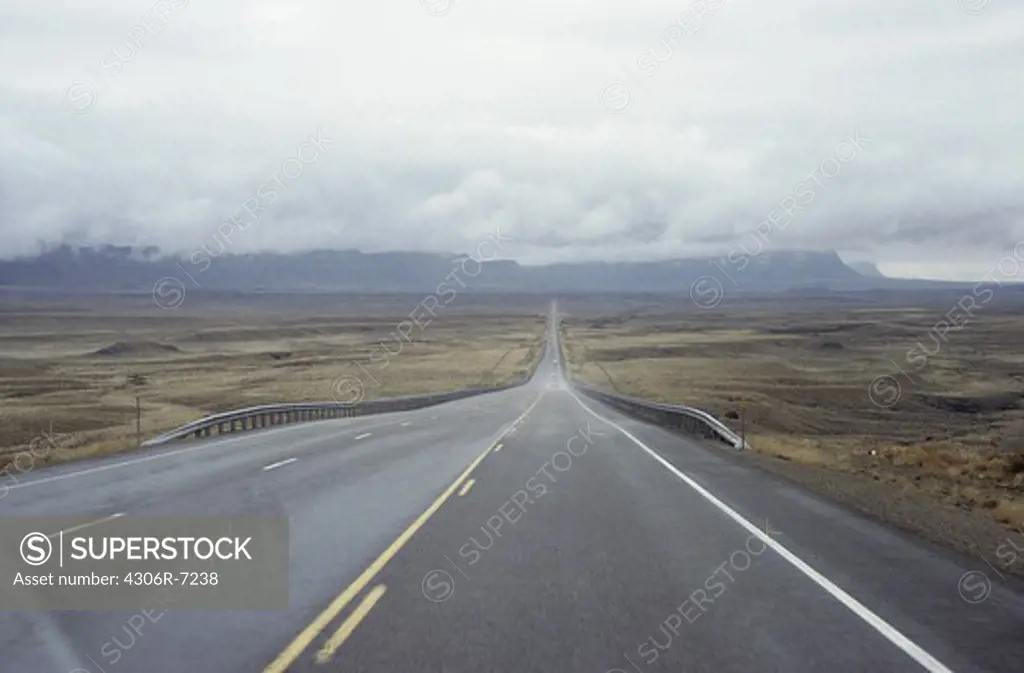 View of straight road passing by barren landscape