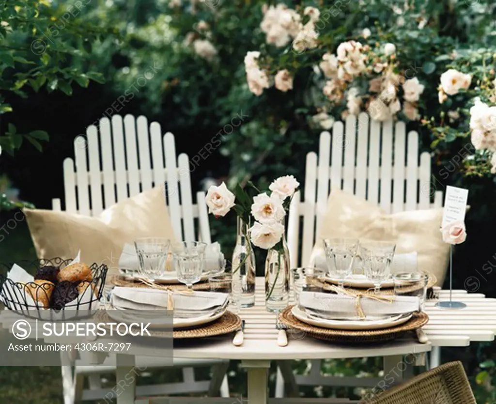 Place setting on wooden table in garden