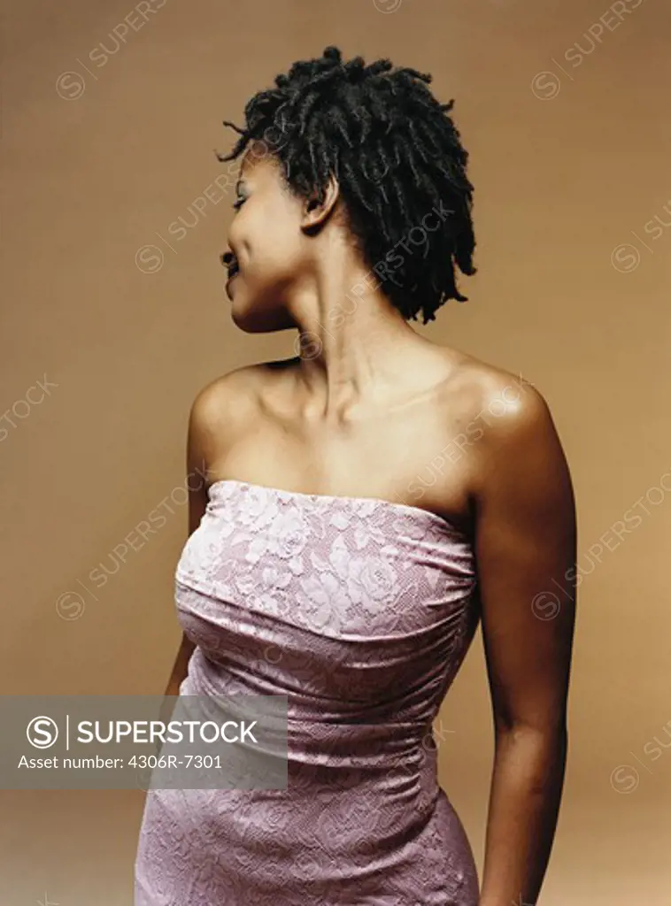 Smiling woman standing and turning back against brown background
