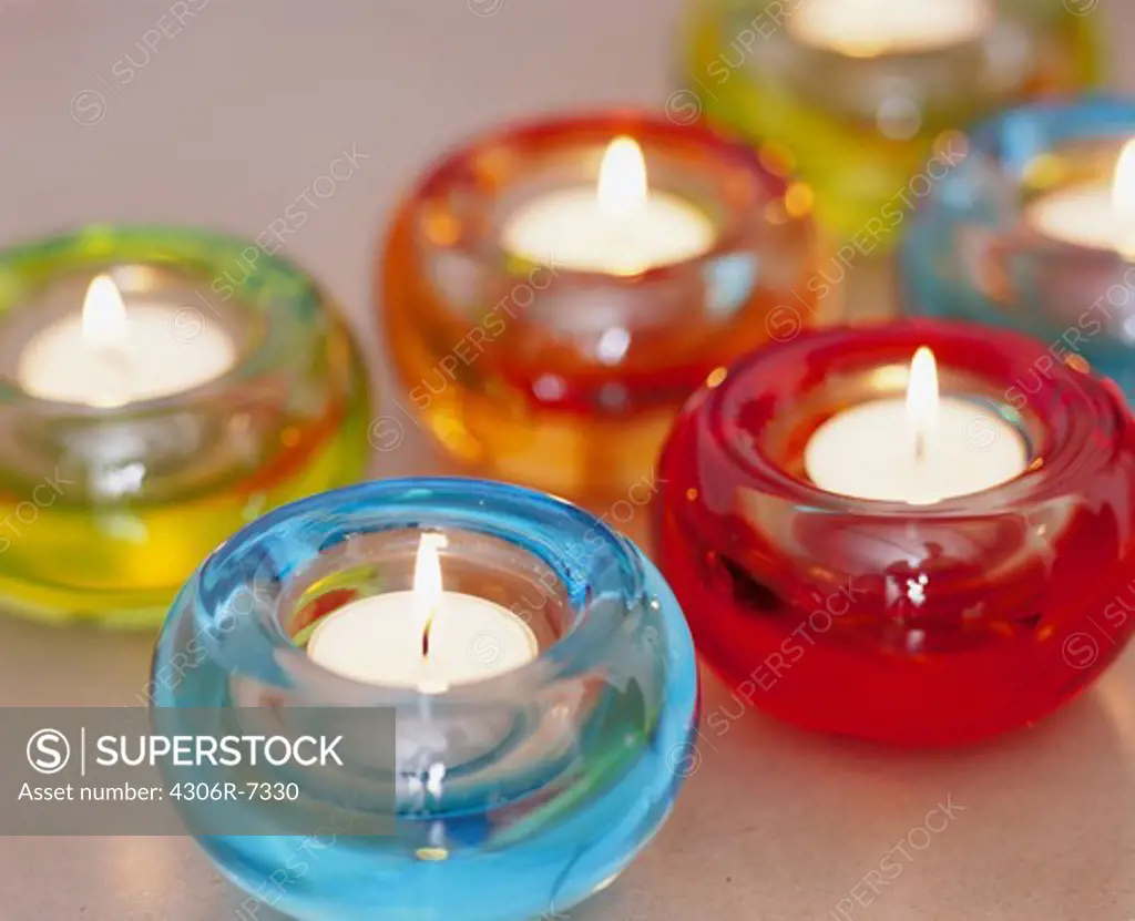 Lighted candles in multicolored bowls