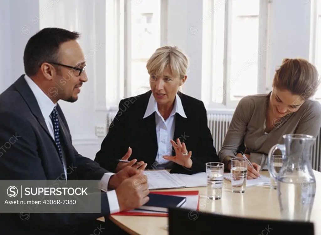 Businessman and women sitting at desk having discussion