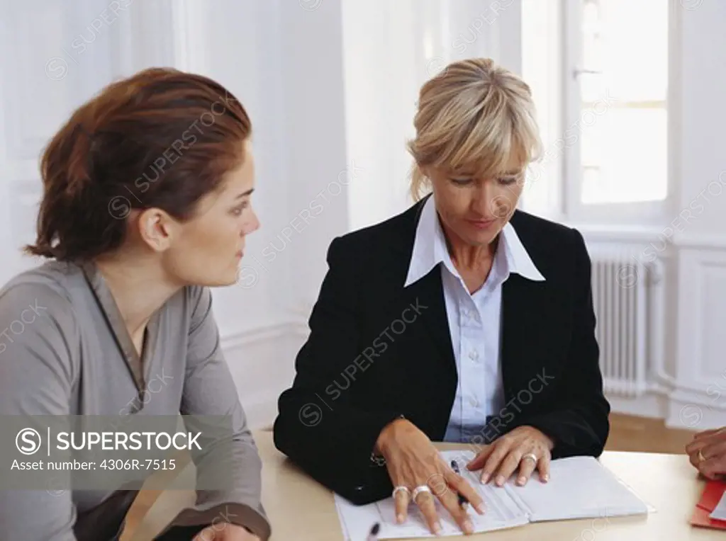 Businesswomen sitting at desk having discussion