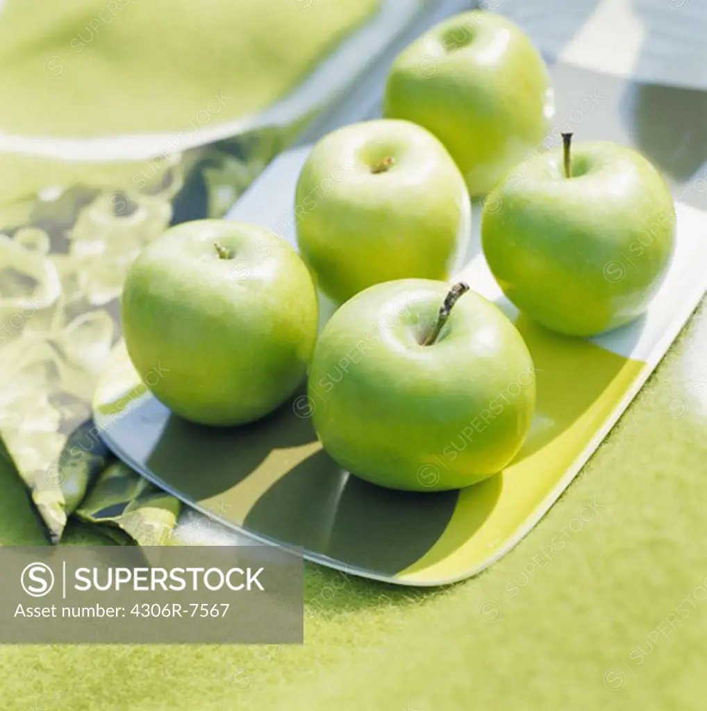 Green apples on tray with napkin on side, close-up