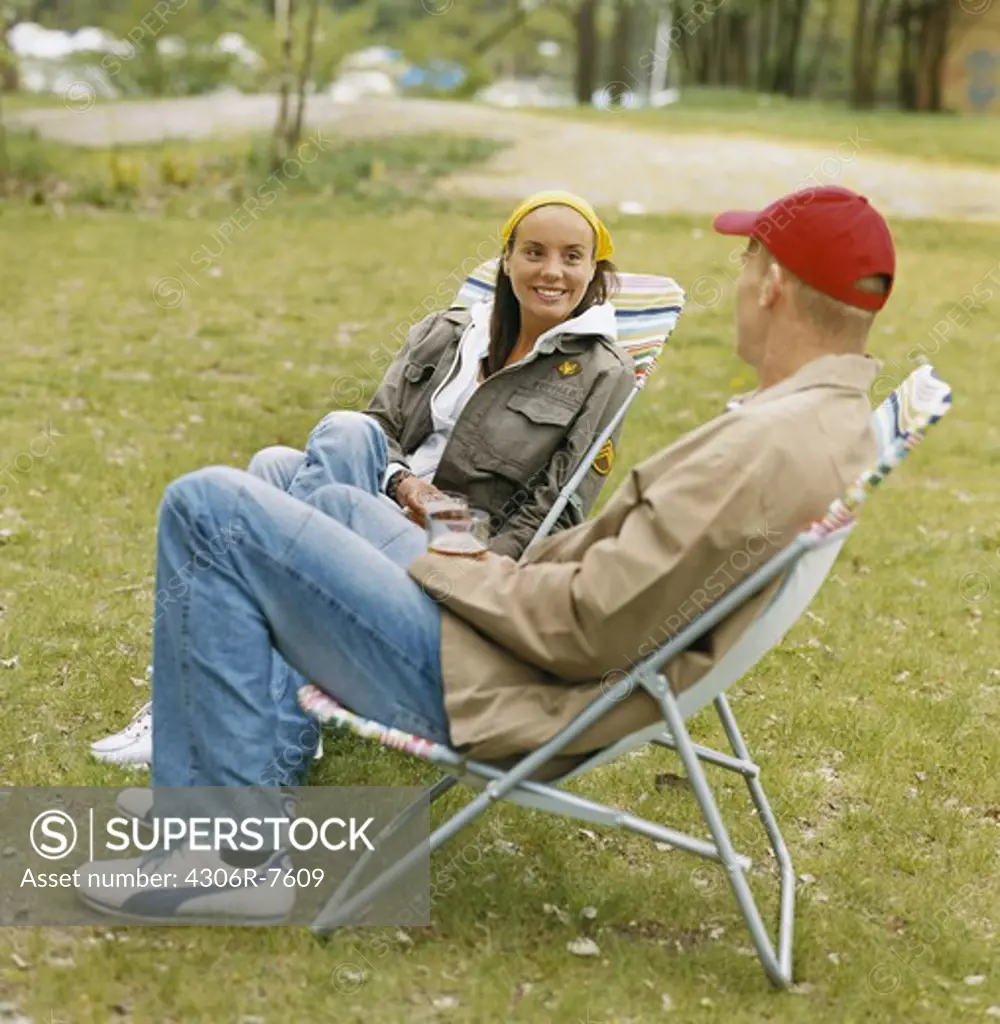 Couple sitting on outdoor chairs in park