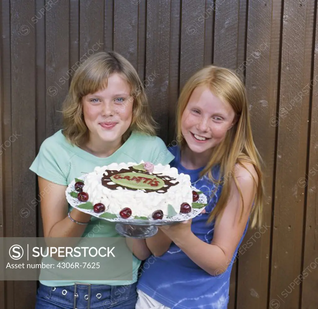 Two girls holding birthday cake