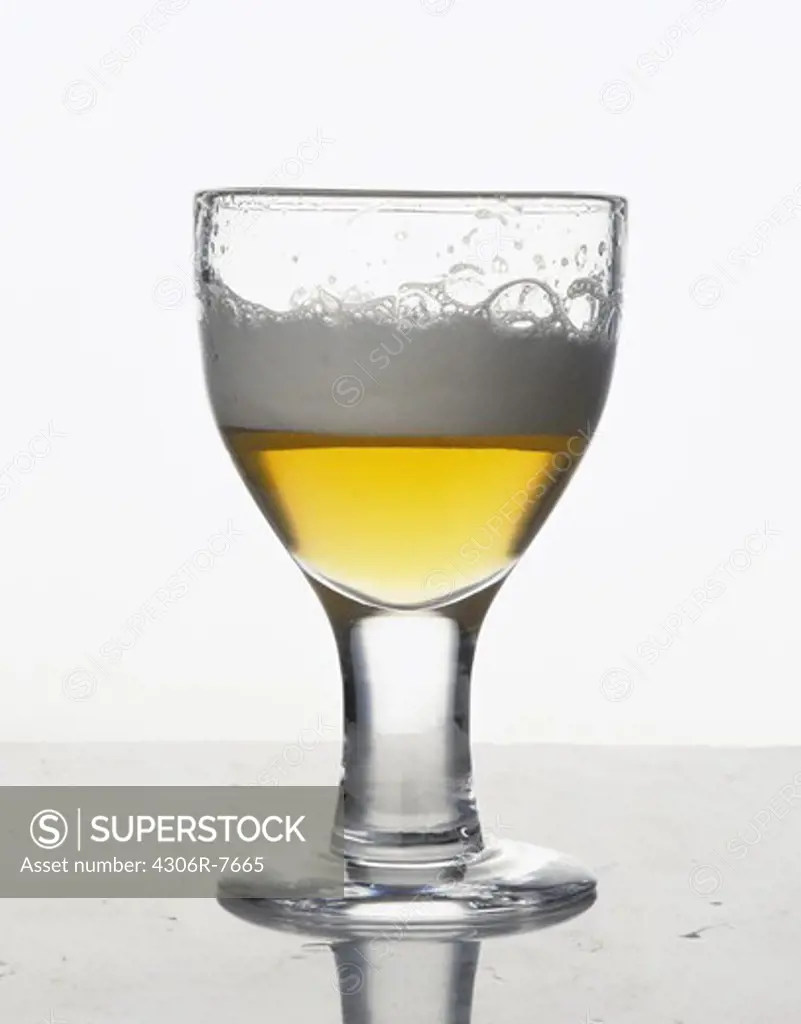 Half full beer glass against white background, close-up