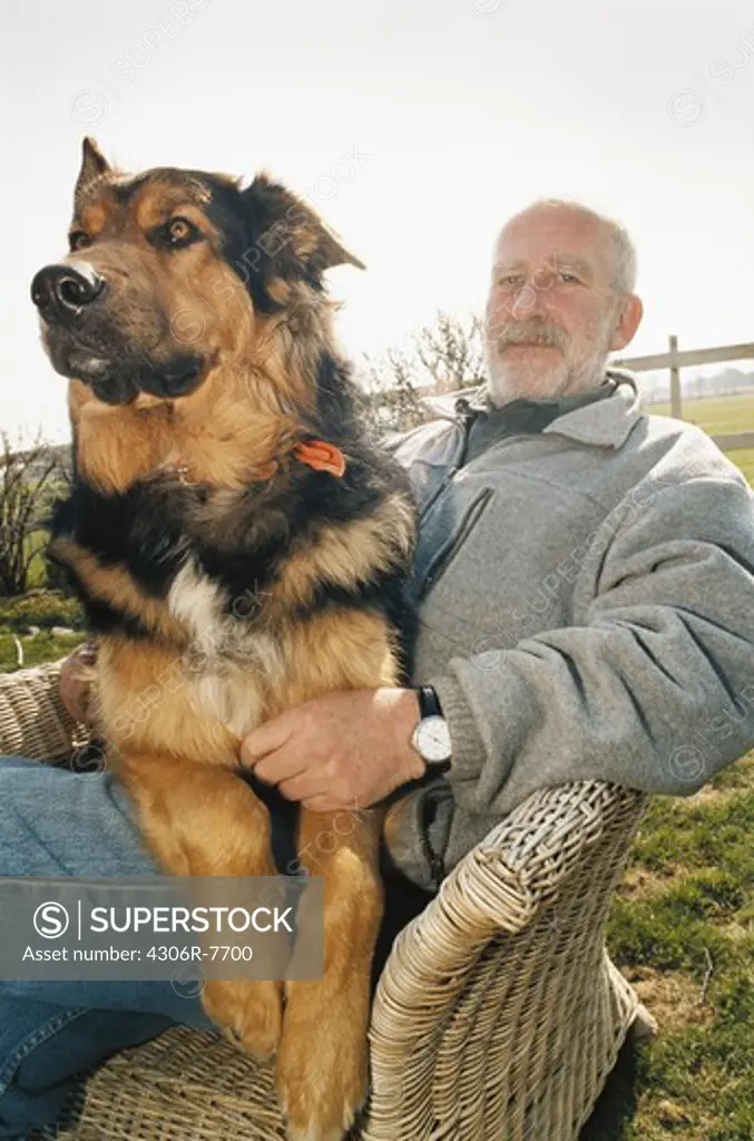 Man sitting on outdoor chair with dog on lap