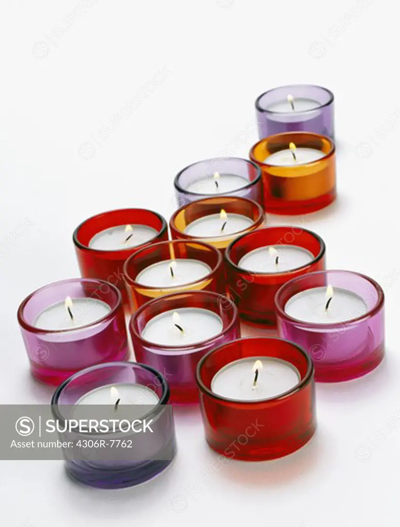 Multicolored lighted candles against white background