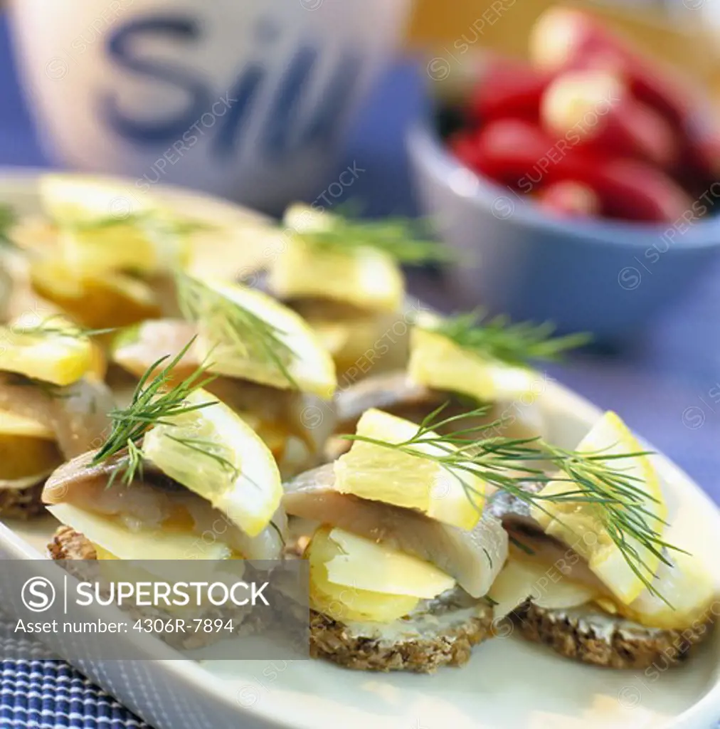 Pieces of herring fish topped with lemon and dill