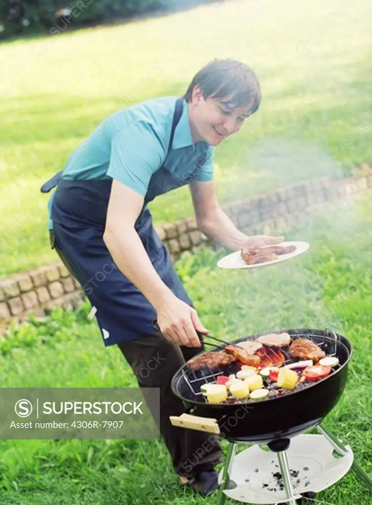 Man cooking on barbecue grill in garden