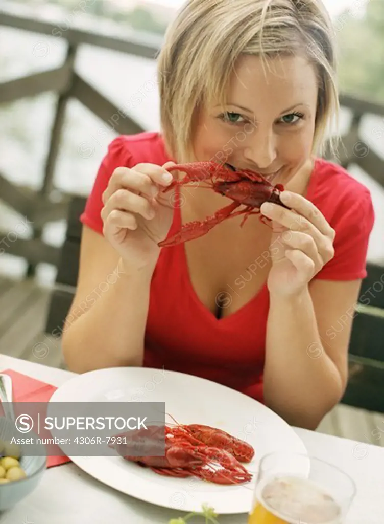 Portrait of woman sitting at outdoor table eating crayfish