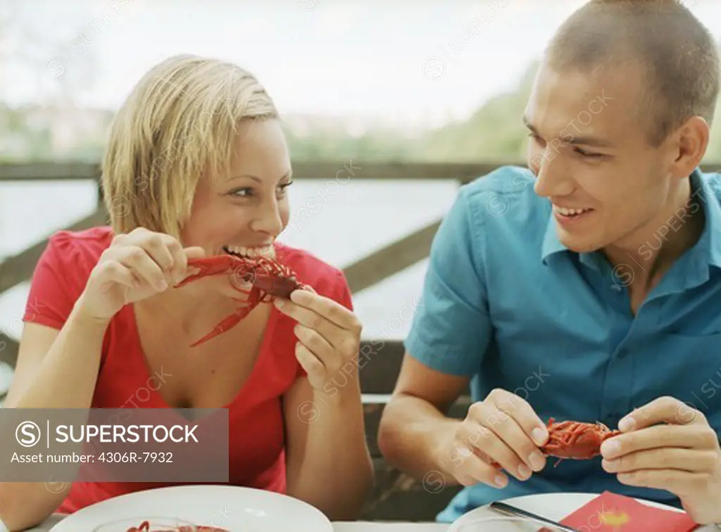 Man and woman sitting at outdoor table eating crayfish