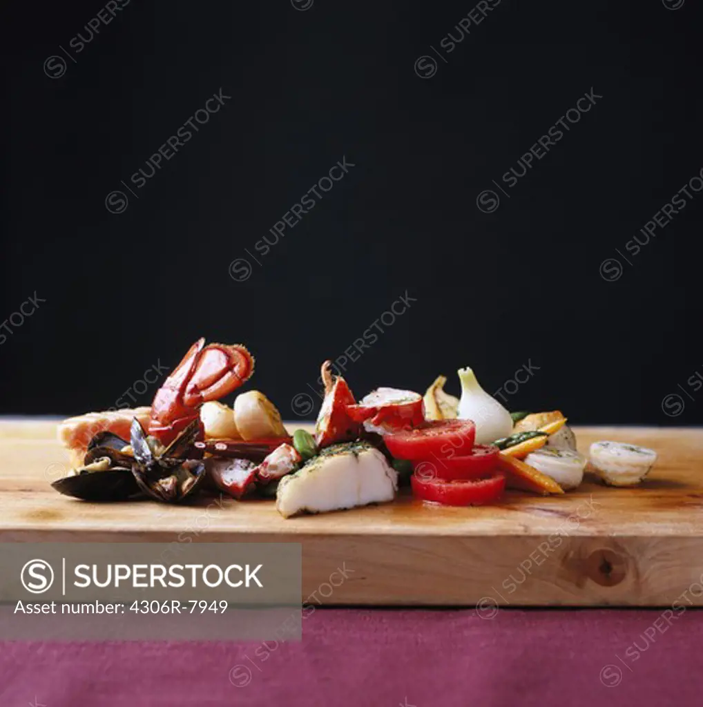 Raw sliced vegetables and shellfish on cutting board