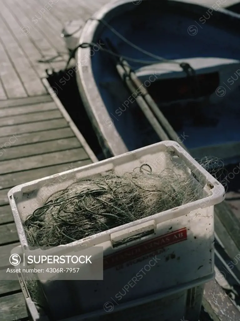 Fishing net kept in box on wooden jetty next to boat