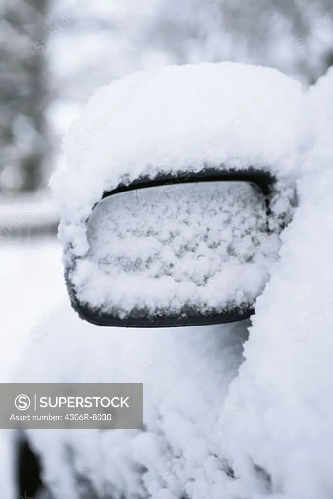Rear view mirror of a car covered with snow