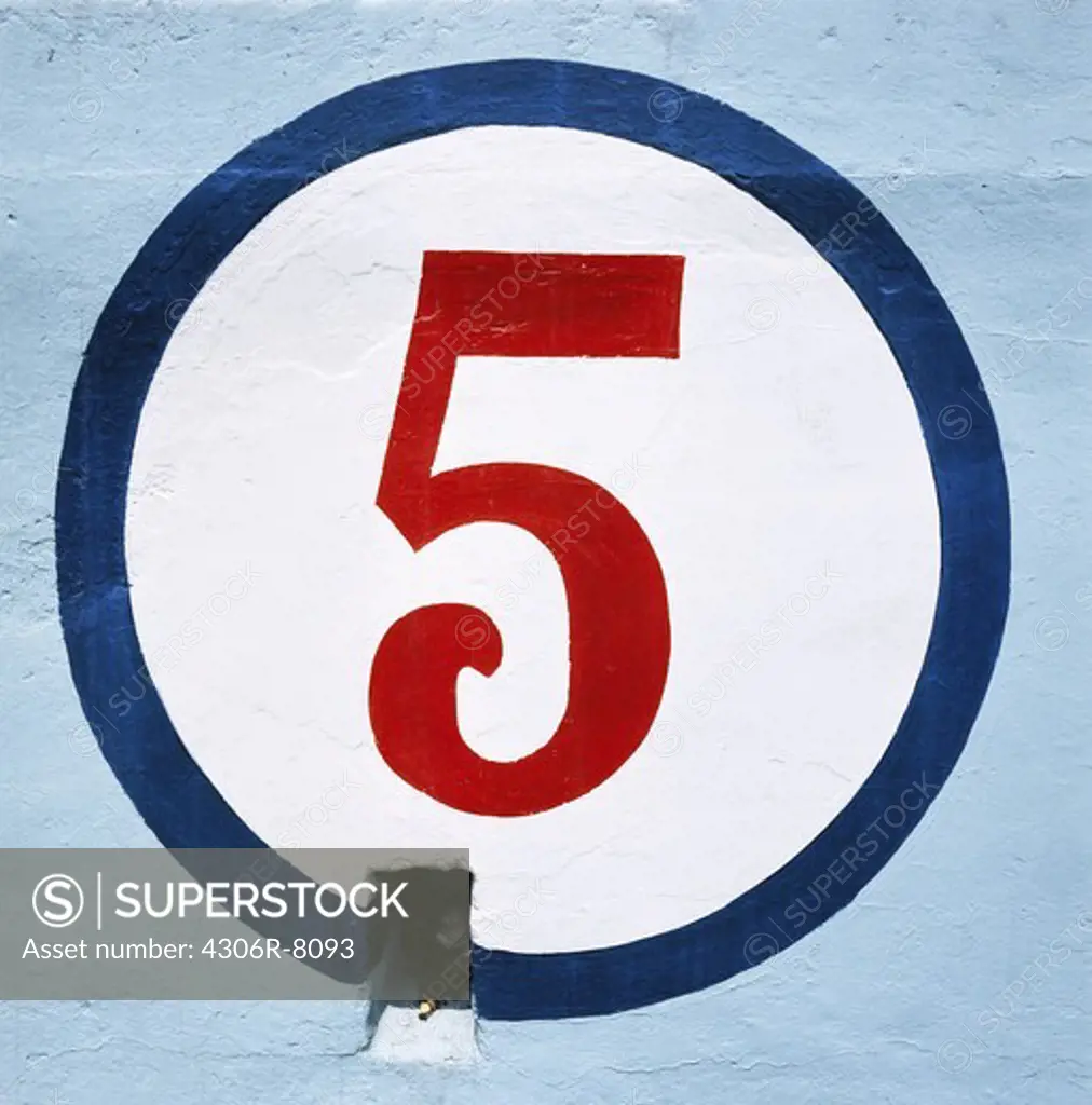 Numeric 'five' written in circle on blue wall