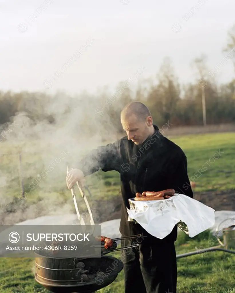 Man removing sausages from barbecue grill