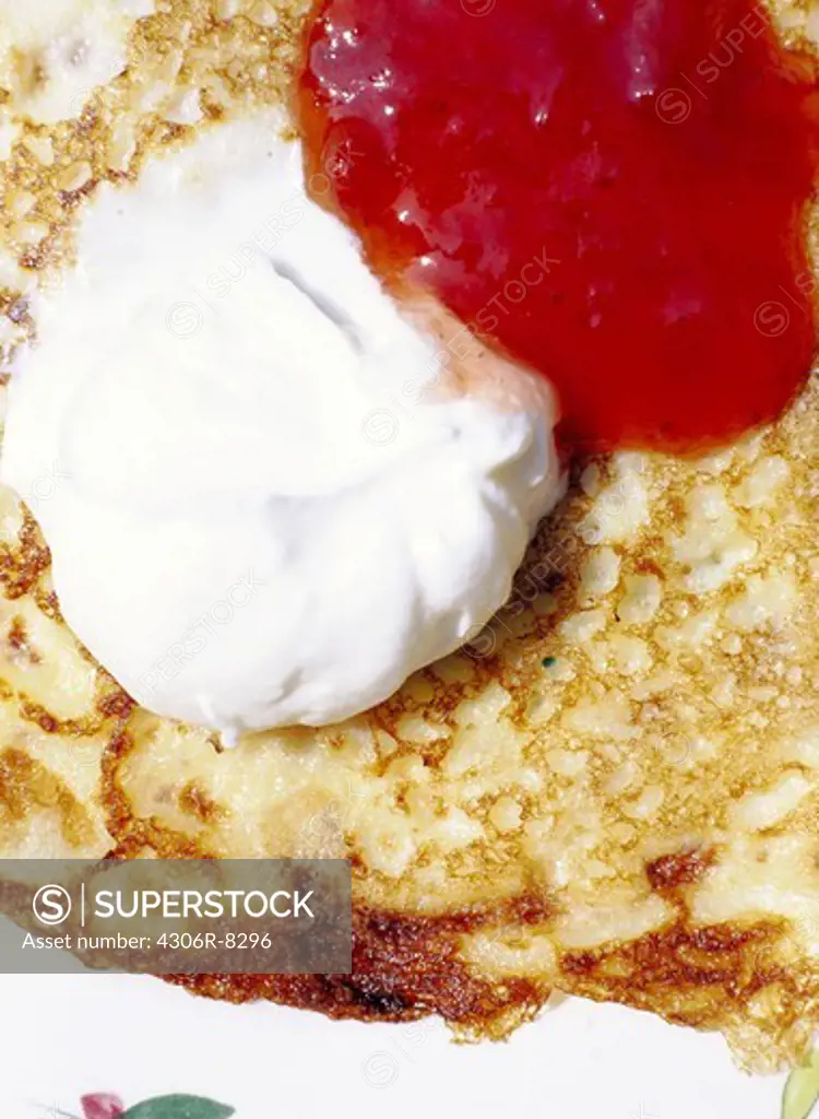 Whipped cream and jam on pancake, close-up