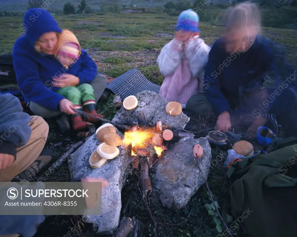 Group of people sitting around campfire