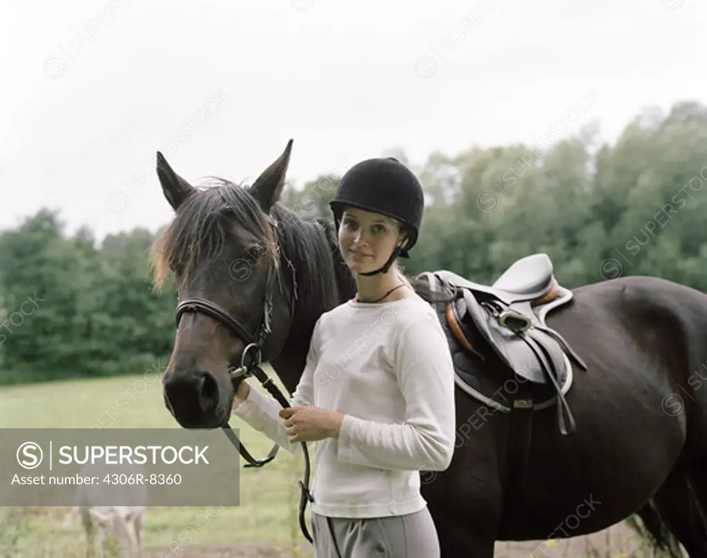Woman wearing riding helmet standing beside horse
