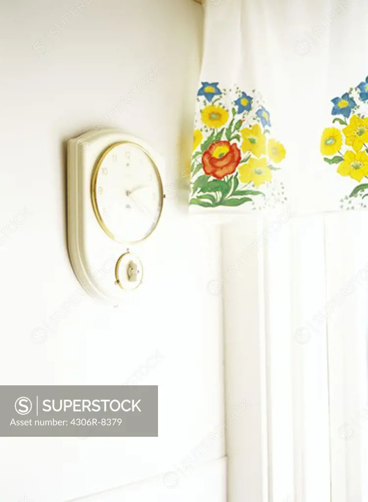 Wall on clock beside floral patterned curtain