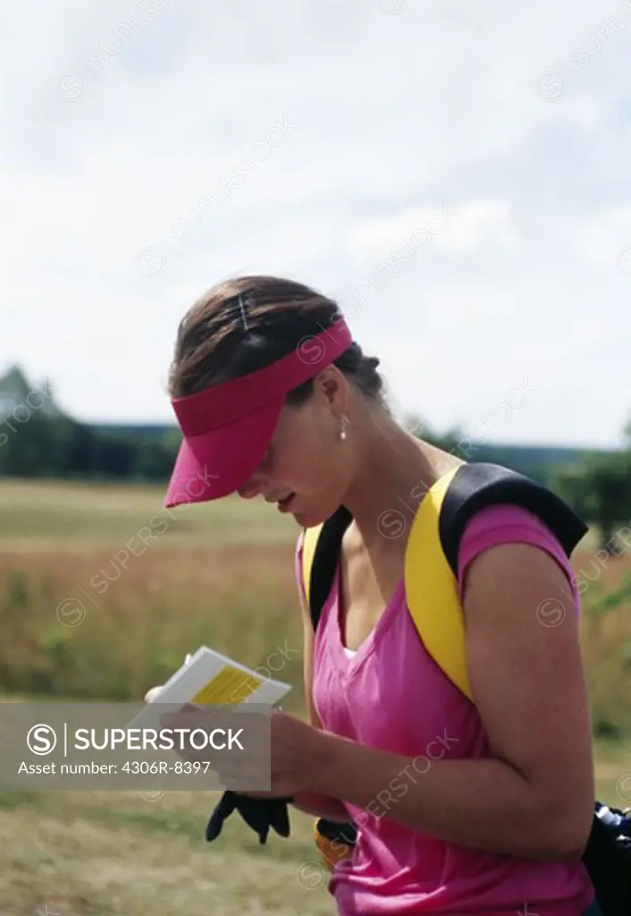 Woman reading from paper in golf course