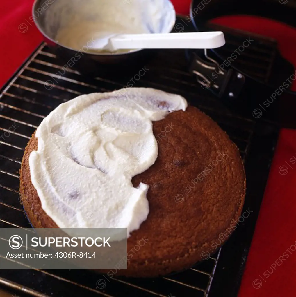Round cake topped with cream on baking tray