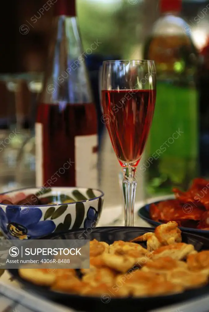 Snacks on plate beside glass of wine on table, close-up