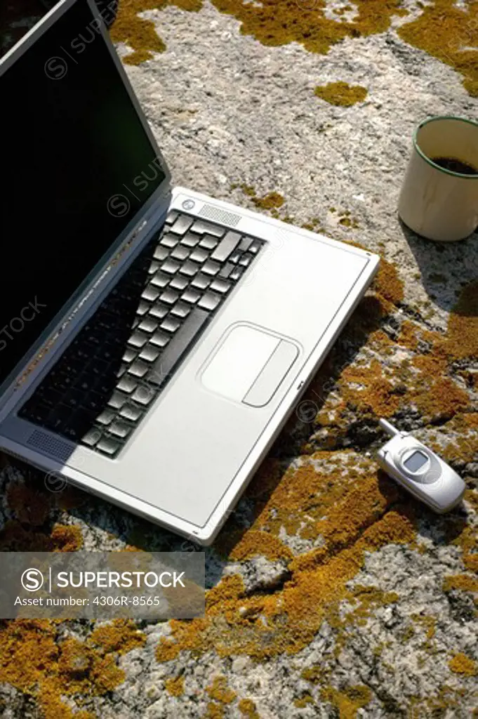 Laptop and mobile phone on rock, close-up