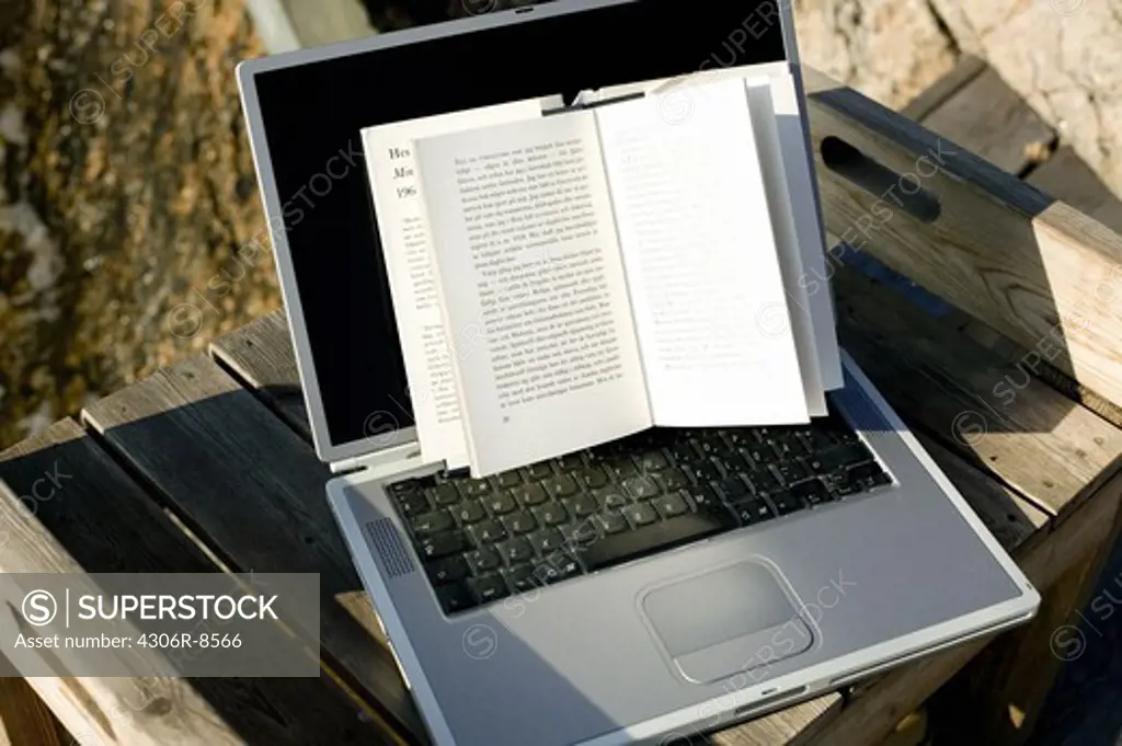 Laptop and book on wooden jetty, close-up
