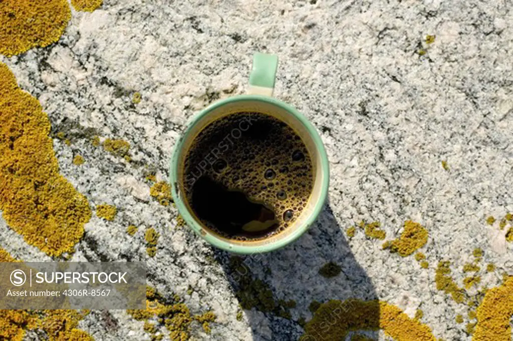 Cup of coffee on rock, close-up
