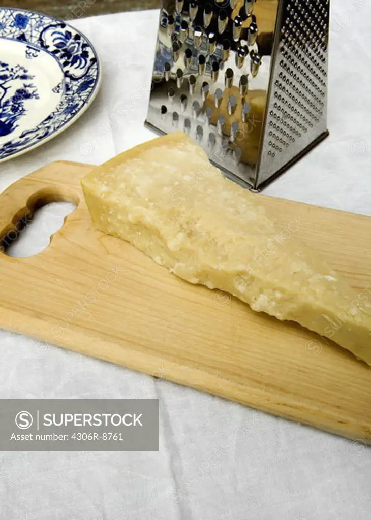 A piece of parmesan cheese on a cutting board, close-up.