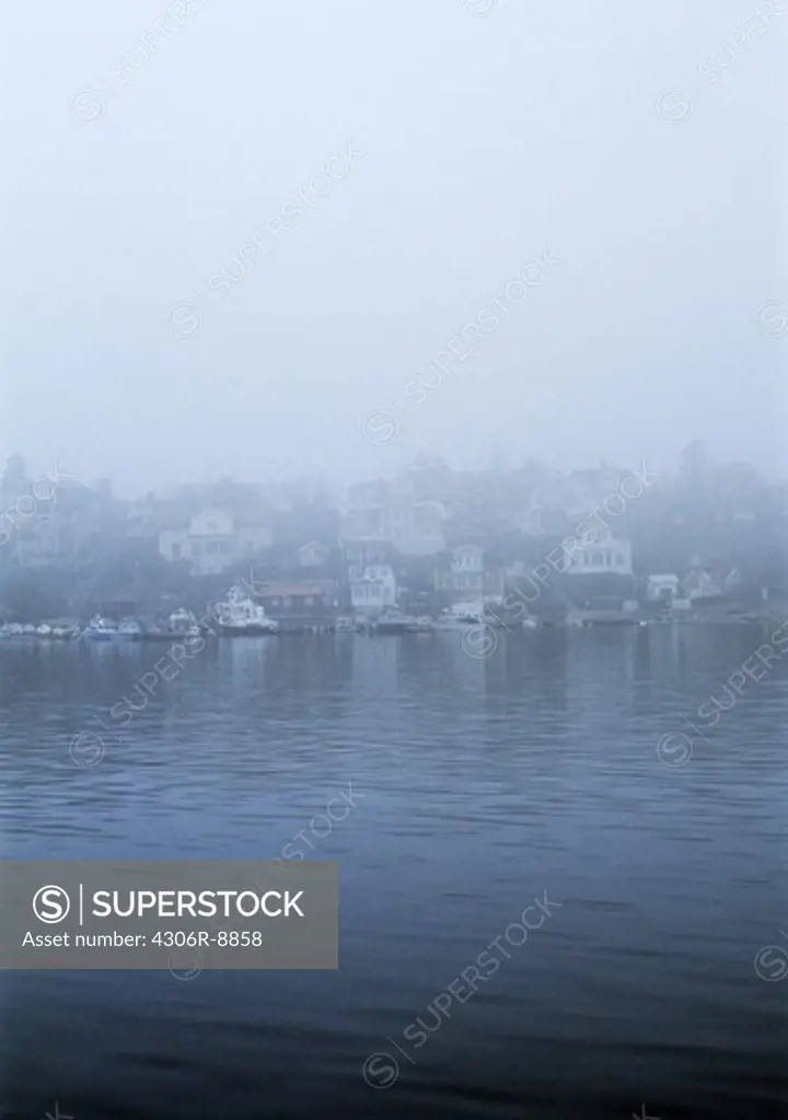 A community by the water concealed in fog.