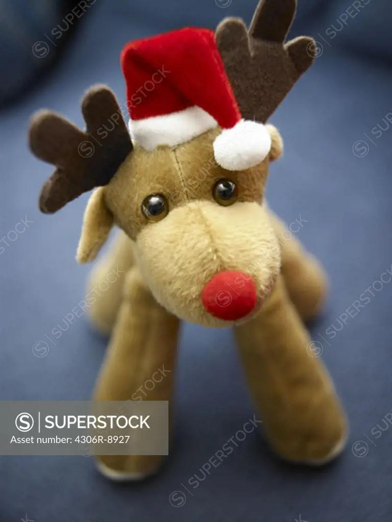 A toy reindeer with a Christmas cap, close-up.