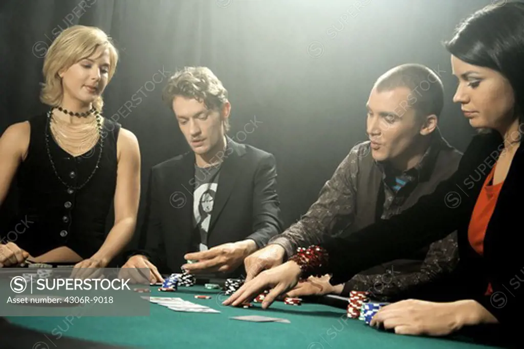 Four people playing poker at a gambling table.