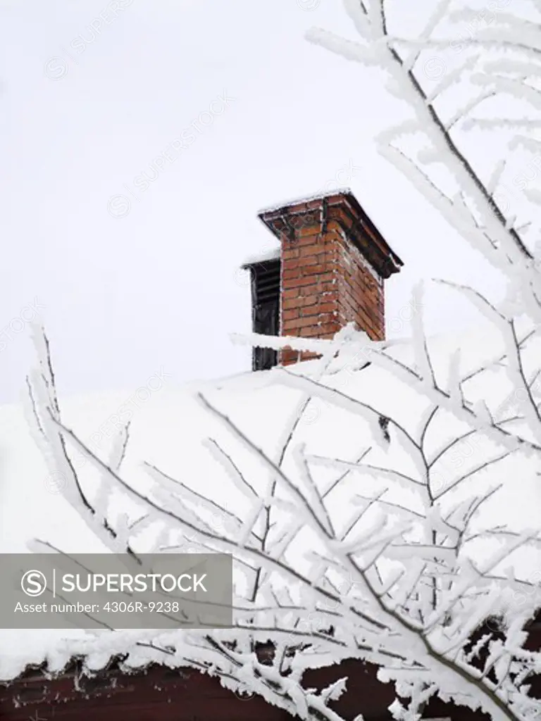 A chimney on a roof covered in snow.