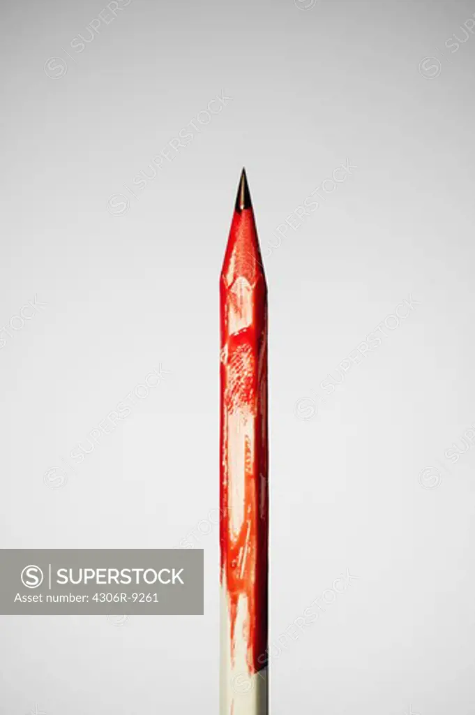 A pencil with red colour on a grey background.
