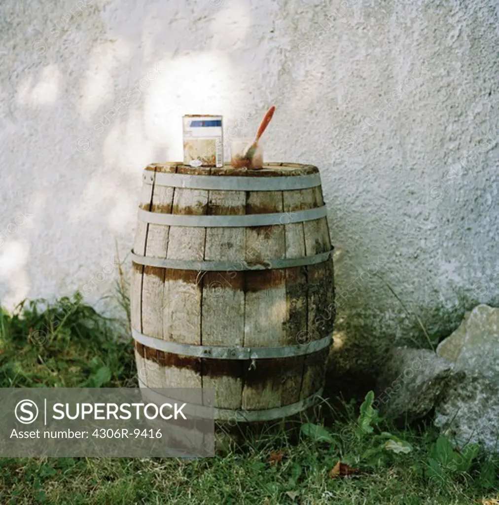 A barrel by a lime brick wall.