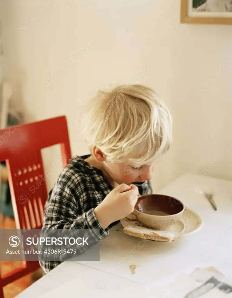 A boy eating soup.