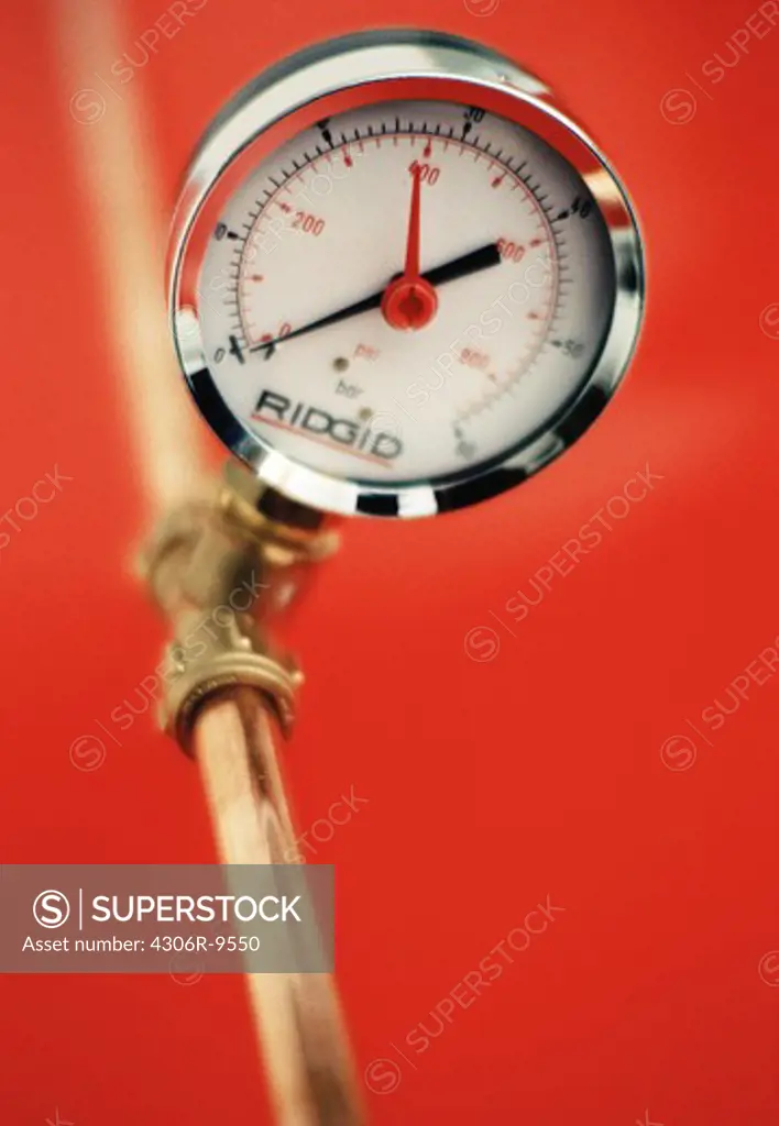 A pressure gauge against a red background.