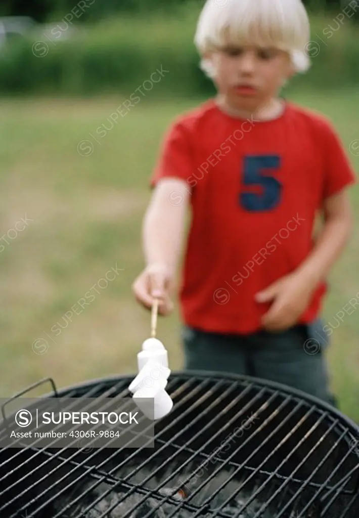 A boy grilling marshmallows.