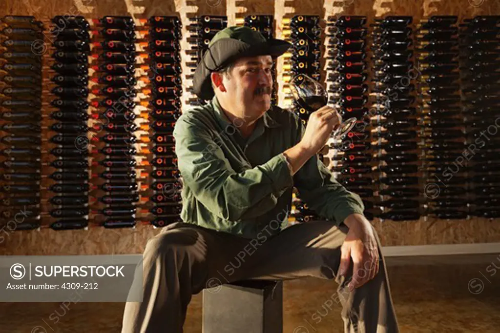 Man tasting wine in a wine storage room.