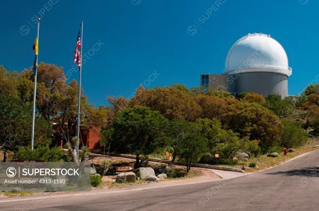 The 2.1-meter Telescope is seen near the flagpoles and sign marking Kitt Peak National Observatory, Arizona.