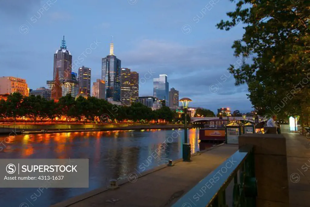 Australia, Victoria, Melbourne, Skyline of city at night along Yarra River looking towards Federation Wharf from Southbank