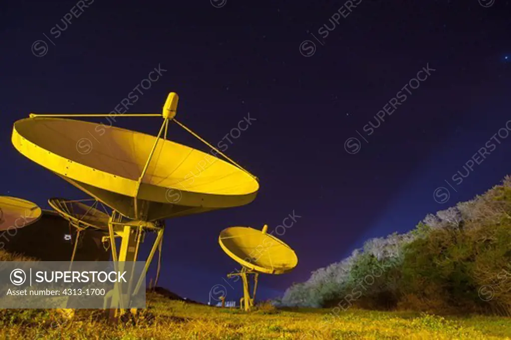 USA, Florida, Cape Canaveral, Kennedy Space Center, view of satellite at night. Satellite dishes bathed in yellow light are seen at night at the Kennedy Space Center in Florida.