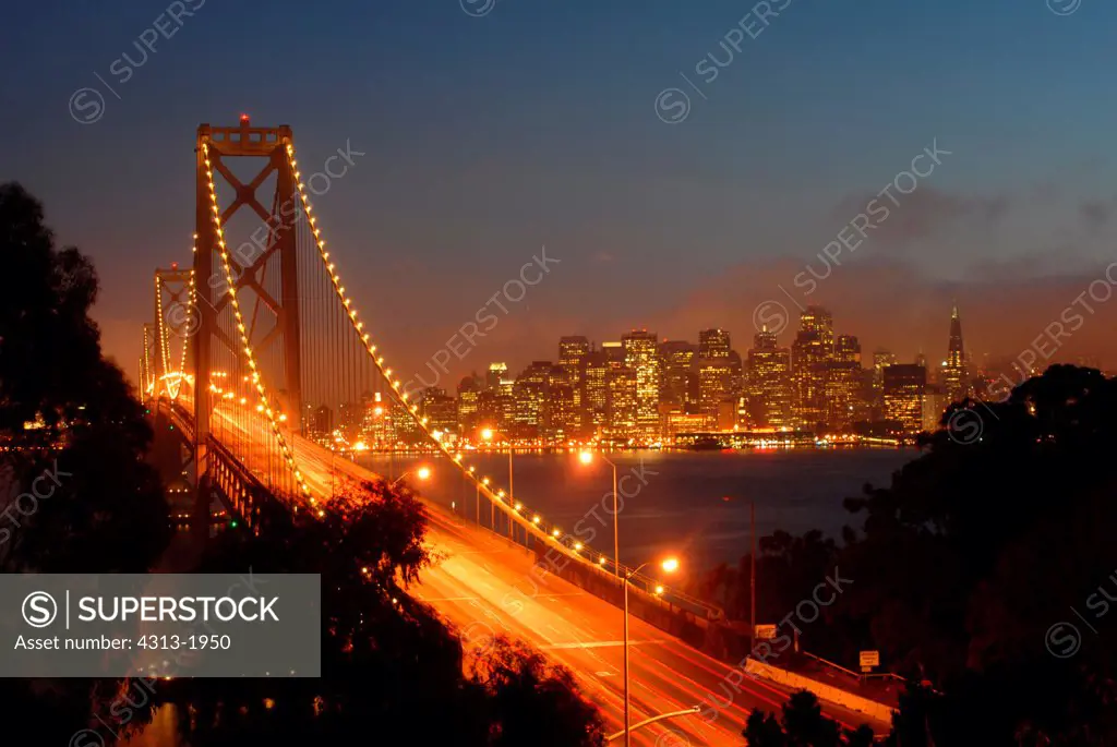 Bay Bridge lit up at dusk with skyline in the background seen from Yerba Buena Island, San Francisco Bay, San Francisco, California, USA