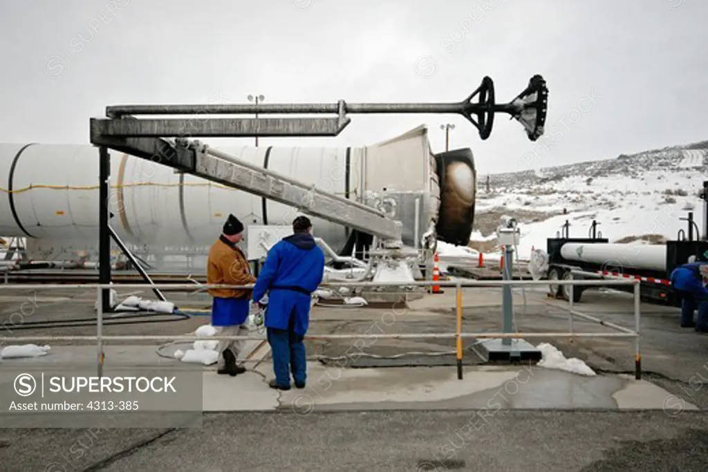 The final space shuttle reusable solid rocket booster to be tested is seen post-firing on a test stand at the ATK site near Promontory, Utah. The large jagged device was used to spray liquid carbon dioxide into the nozzle to rapidly extinguish the booster after firing.