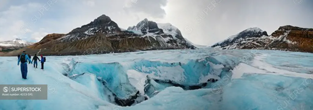 Panoramic view of Athabasca Glacier. Hikers complete with crampons walk near a large crevasse atop Athabasca Glacier in the Canadian Rockies, inside Jasper National Park